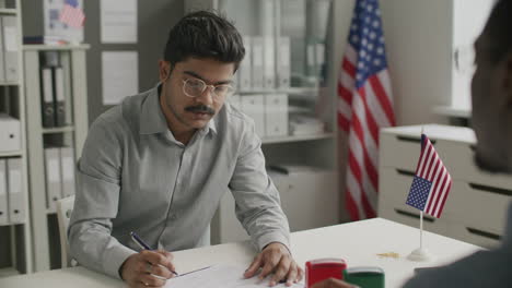 indian man filling out visa application form in us embassy