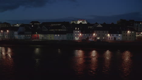 aerial orbit of the iconic long walk in galway at night, showcasing light reflections on the water in a stunning establishing shot