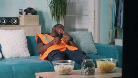 man relaxing on couch watching tv