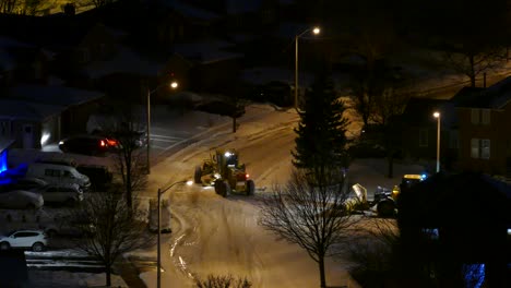 high angle view of two snow plow tractors removing snow from the road with no traffic movement at night