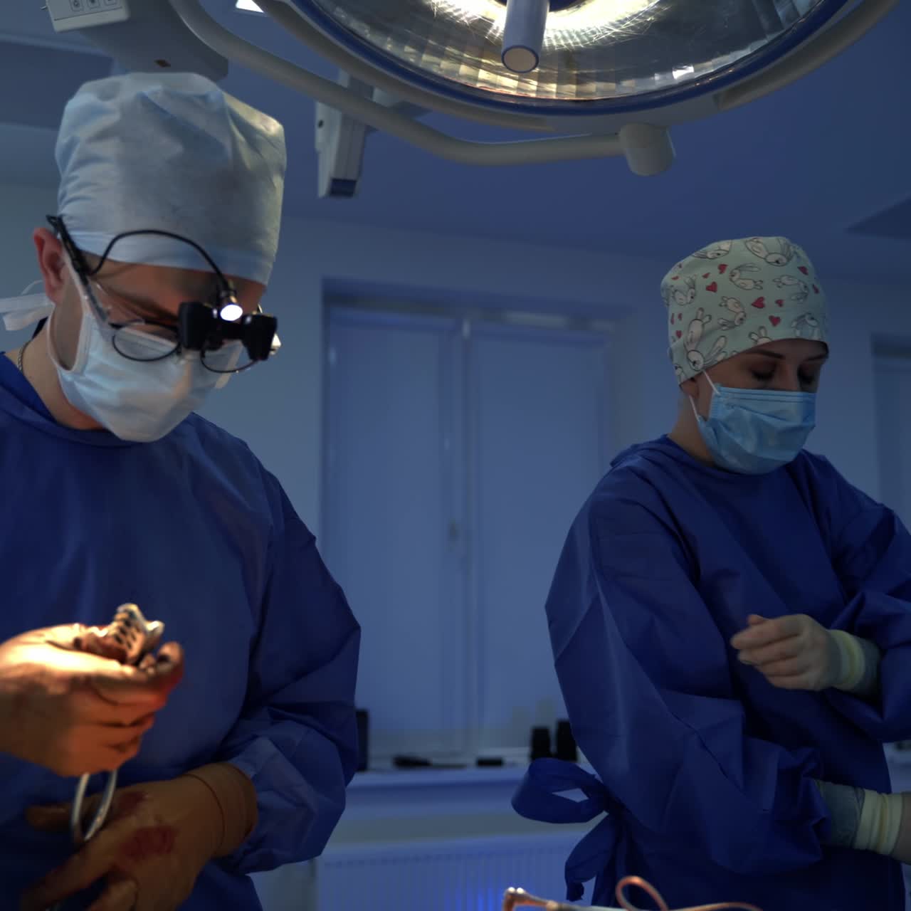 Surgical procedure in the operating theatre. Professional doctor in glasses and microscope lenses perform a neurosurgery. Nurse giving sterile tools to a surgeon