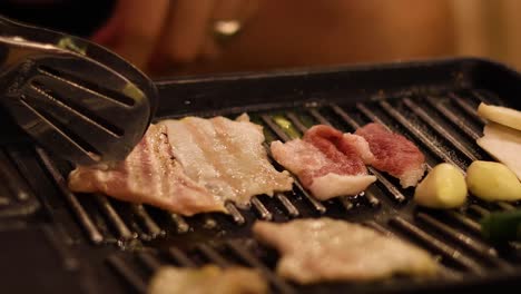 cooking bacon strips and vegetables on a grill