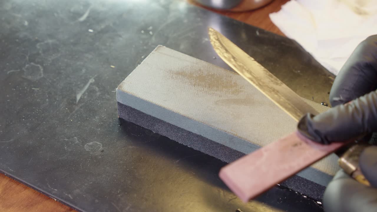 el borde del cuchillo de caza está afilado a la navaja afilada con piedra afilada, guantes de mano