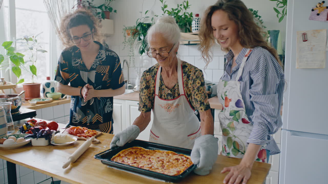 Anziana sorridente e nipoti che mettono la pizza appena sfornata sul tavolo
