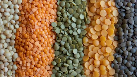 colorful lentils forming undulating pattern on white background, displaying vibrant gradient of red, green, yellow and brown legumes in artistic arrangement