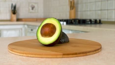 close up of sliced hass avocado. half of avocado. rotating camera with white kitchen on the background. dolly-shot.