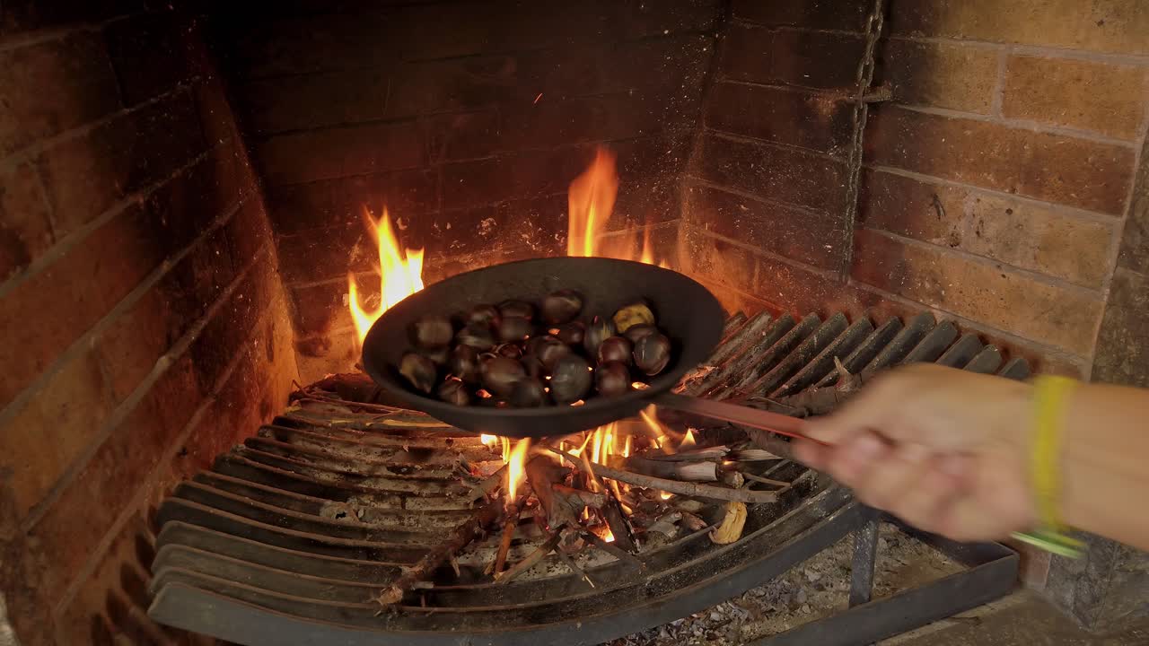 sacudindo castanhas enquanto cozinham em uma panela perfurada sobre o fogo