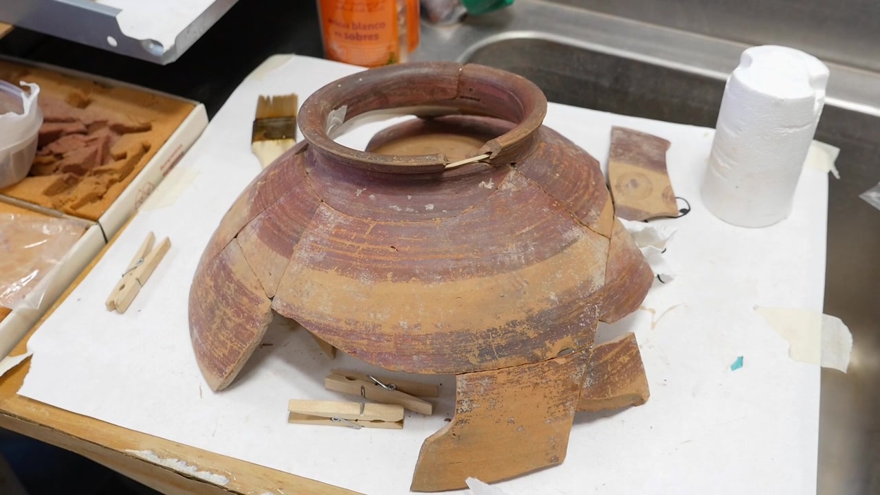 Fragments of ancient pottery have been sorted up to a large clay vase that is being restored and reconstructed in a laboratory.
