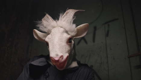 person wearing a goat mask in a dark alley