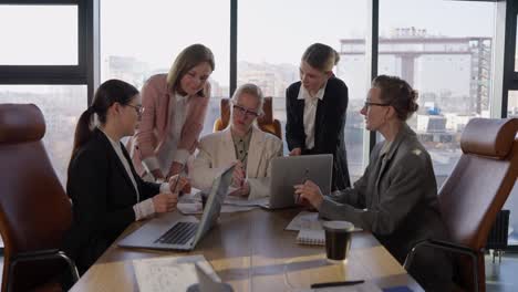 Side-view-of-a-confident-middle-aged-blonde-girl-in-a-white-business-suit-communicates-with-her-colleagues-during-a-meeting-and-listens-to-their-suggestions-and-ideas-while-working-in-the-office