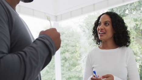 feliz pareja biracial cepillándose los dientes en un baño soleado, cámara lenta