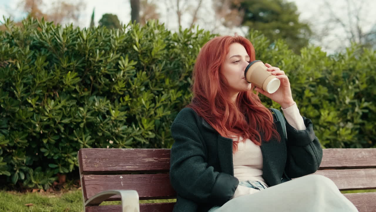 Thoughtful Young Woman Sips Coffee on Park Bench