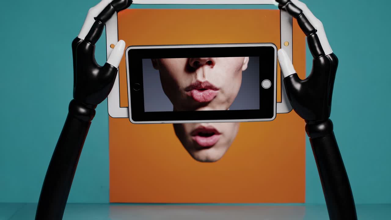 manos robóticas sosteniendo una tableta y un teléfono mostrando la cara de una mujer con la boca abierta