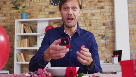 Portrait-of-caucasian-man-showing-a-ring-on-videocall-at-home