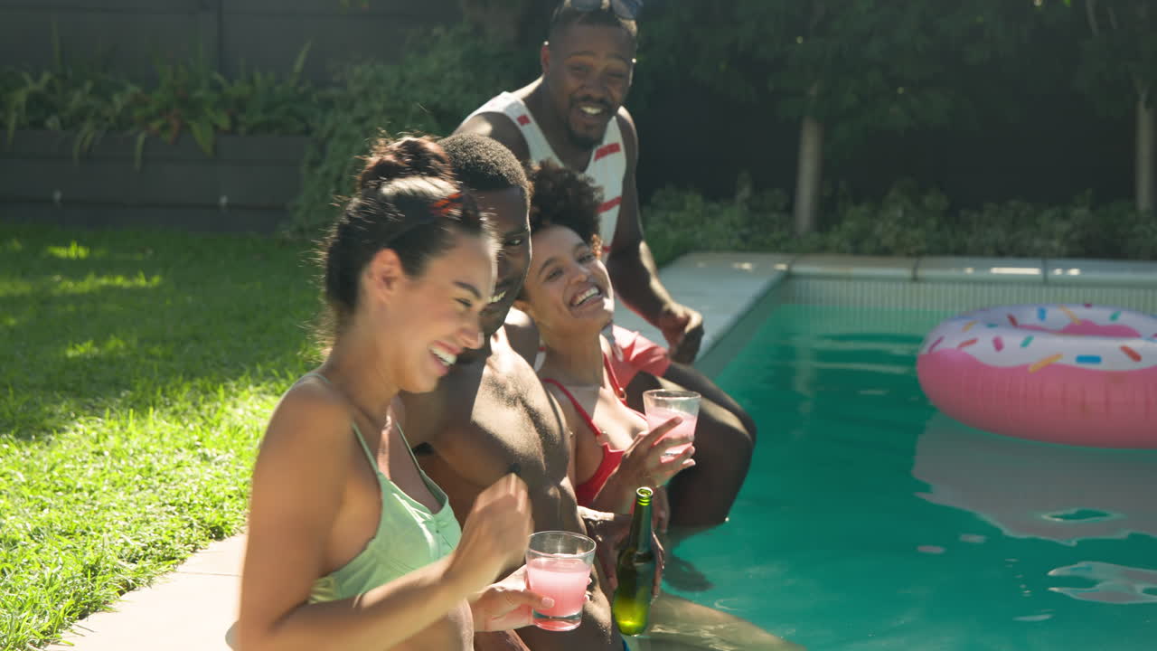 Diverse friends relaxing by pool, enjoying drinks and sunshine, sharing laughter and joy