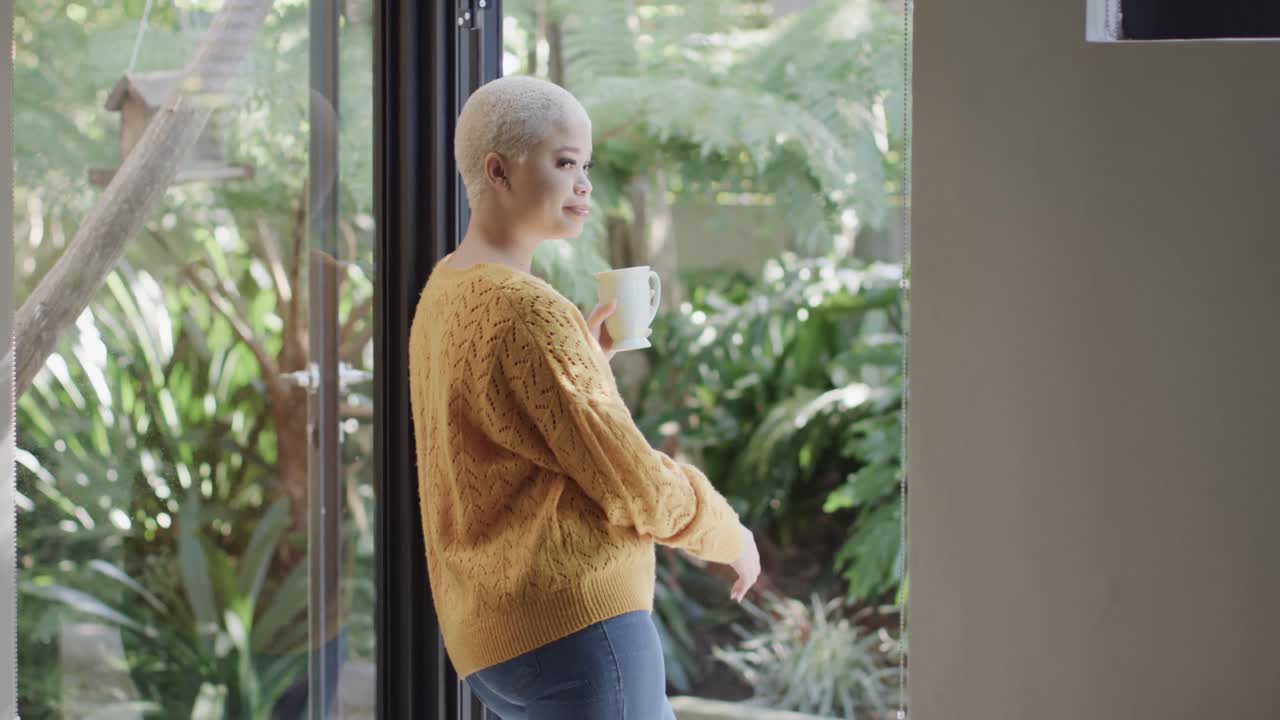 슬로우 모션으로 집의 창문에서 커피를 마시는 행복한 두 인종 여성