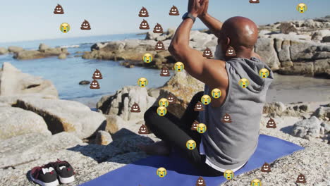 Animation-Von-Emoji-Symbolen-über-Einem-älteren-Afroamerikanischen-Mann,-Der-Am-Strand-Meditiert