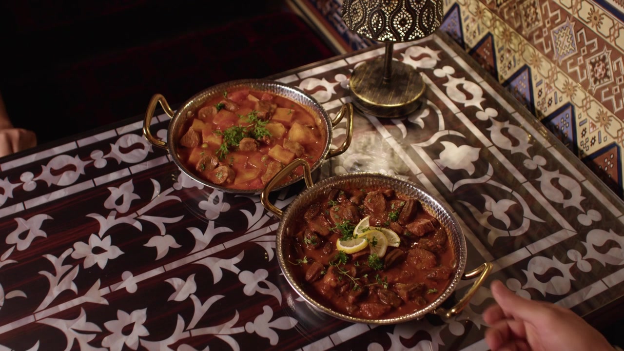 Two traditional Turkish stews served in metal bowls on an ornate patterned table