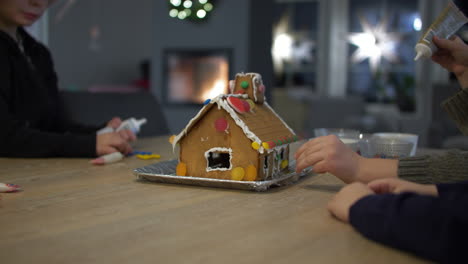 static view of children preparing ginger bread house with candy at christmas