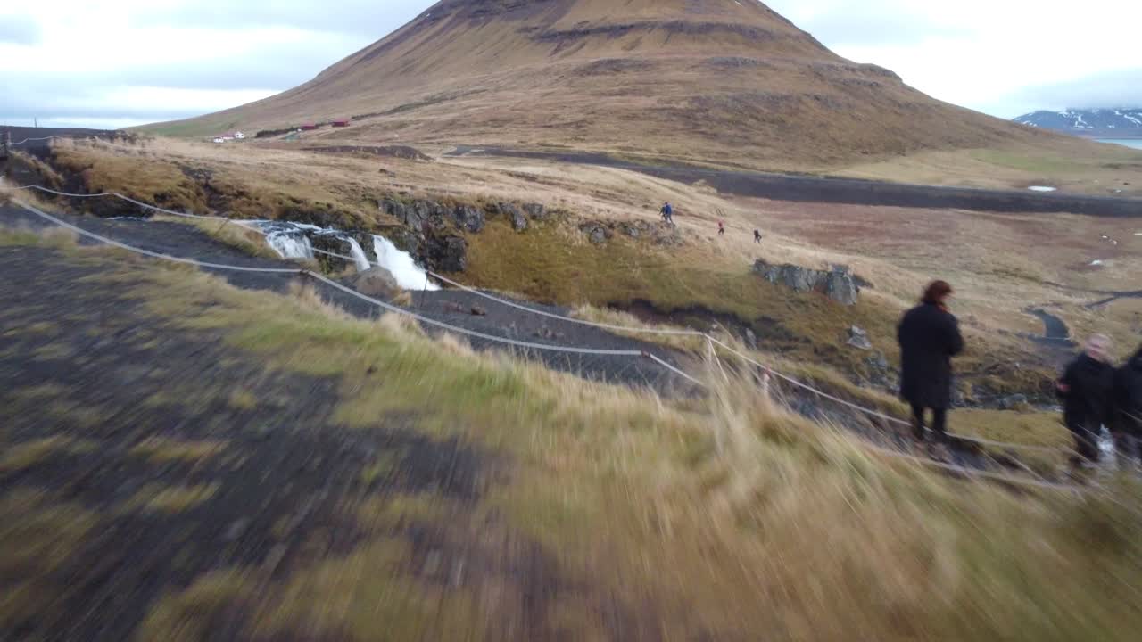아이슬란드의 유명한 폭포인 키르주펠스포스 앞에 서 있는 여성