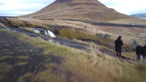 mujer parada frente a kirkjufellsfoss, la famosa cascada de islandia