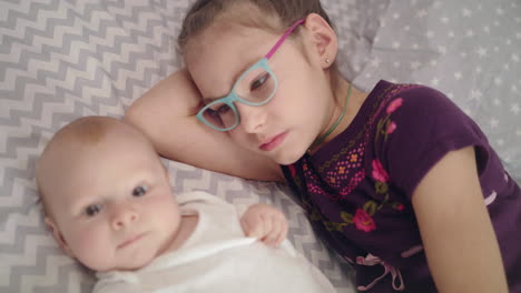 girl kissing baby lying on sofa