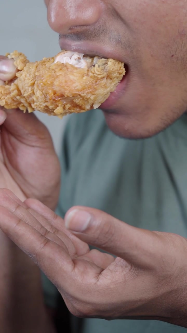 Young Man Eating Crispy Fried Chicken Leg