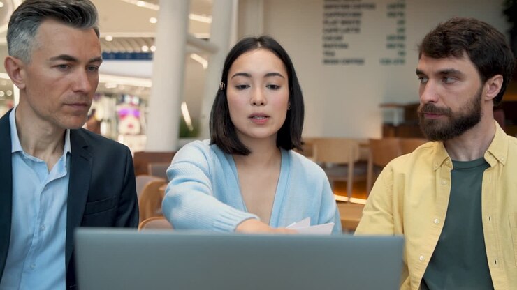 A Work Team Discussing Financial Results On A Laptop At A Meeting In A Coffee Shop