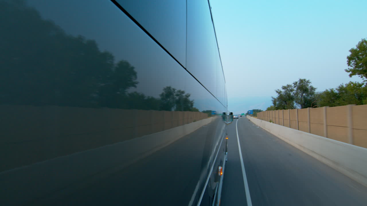 Vista laterale di un autobus pubblico, navetta o scuolabus in movimento e il riflesso della strada su di esso
