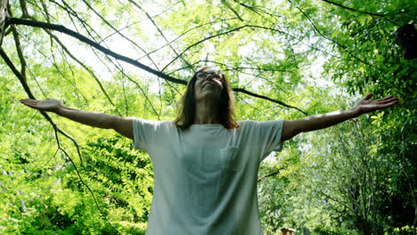 Mature-woman-standing-with-arms-outstretched-in-the-garden-4k