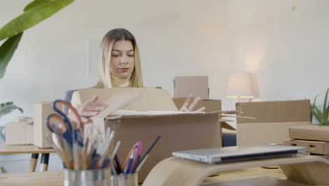 young caucasian lady packing goods in cardboard parcel