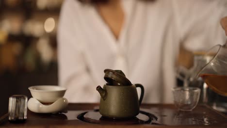 close-up shot of a woman pouring tea into a cup from a teapot, a tea ceremony