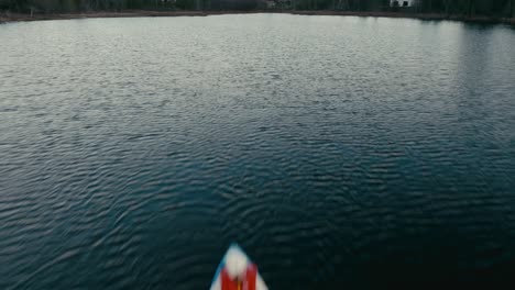 drone fly over a person kayaking on a lagoon with waterfront cabins