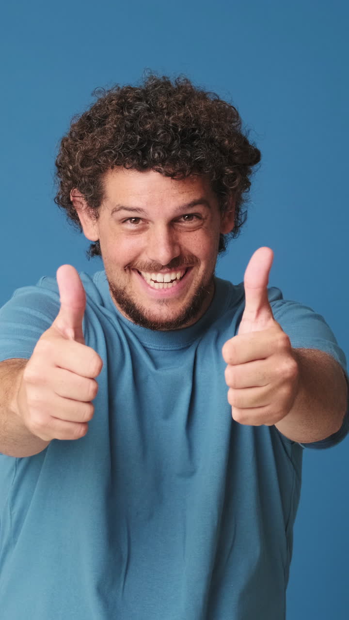 Hombre feliz haciendo un gesto de doble pulgar hacia arriba sobre fondo azul