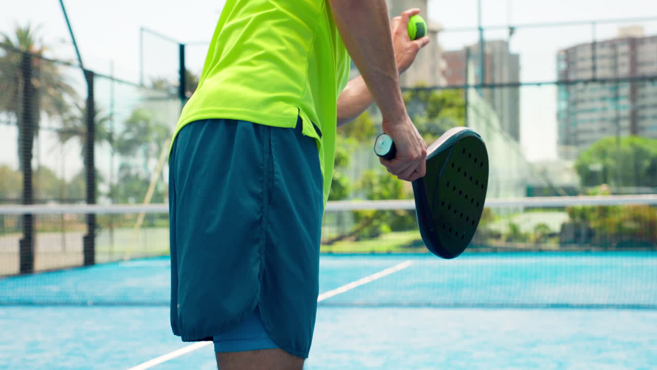 Man Serving Padel Ball on an Outdoor Court