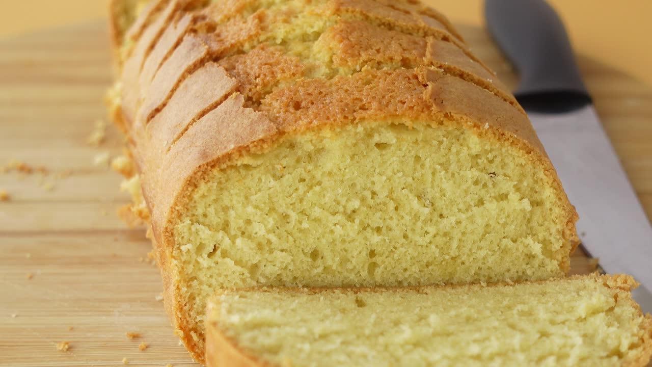 A loaf of cake sliced on a cutting board with a knife