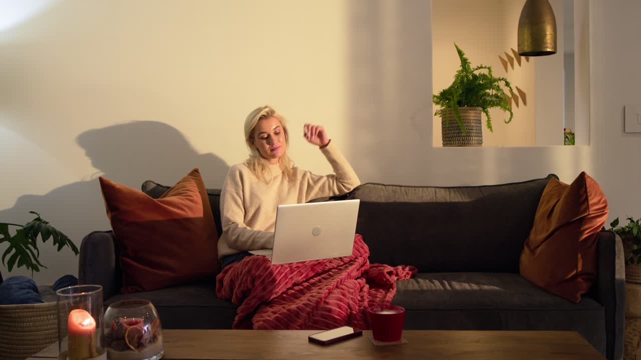 Woman noticing sunlight streaming, pausing before resuming work typing on laptop at home