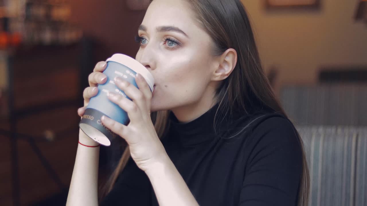 joven y hermosa chica con ojos azules sentada en un café con una taza de café