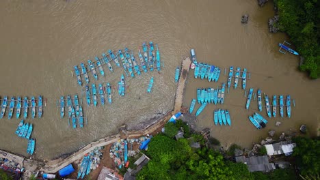 sliding drone shot of rows of fishing boats parked at the fish auction harbor after returning to sea to find fish - baron beach, indonesia