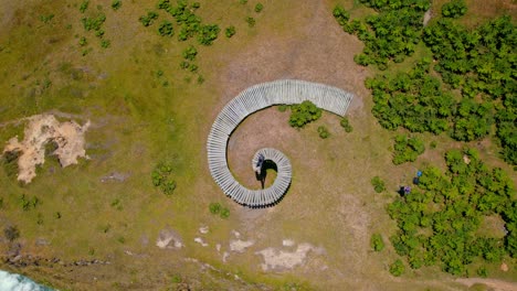 Luftdrohne-Rotiert-über-Spiralförmigem-Holzpfad,-Muelle-Del-Tiempo,-Grüne-Uferwellen,-Strandlandschaft-Bei-Chiloé,-Chilenisches-Patagonien,-Soul&#39;s-Dock