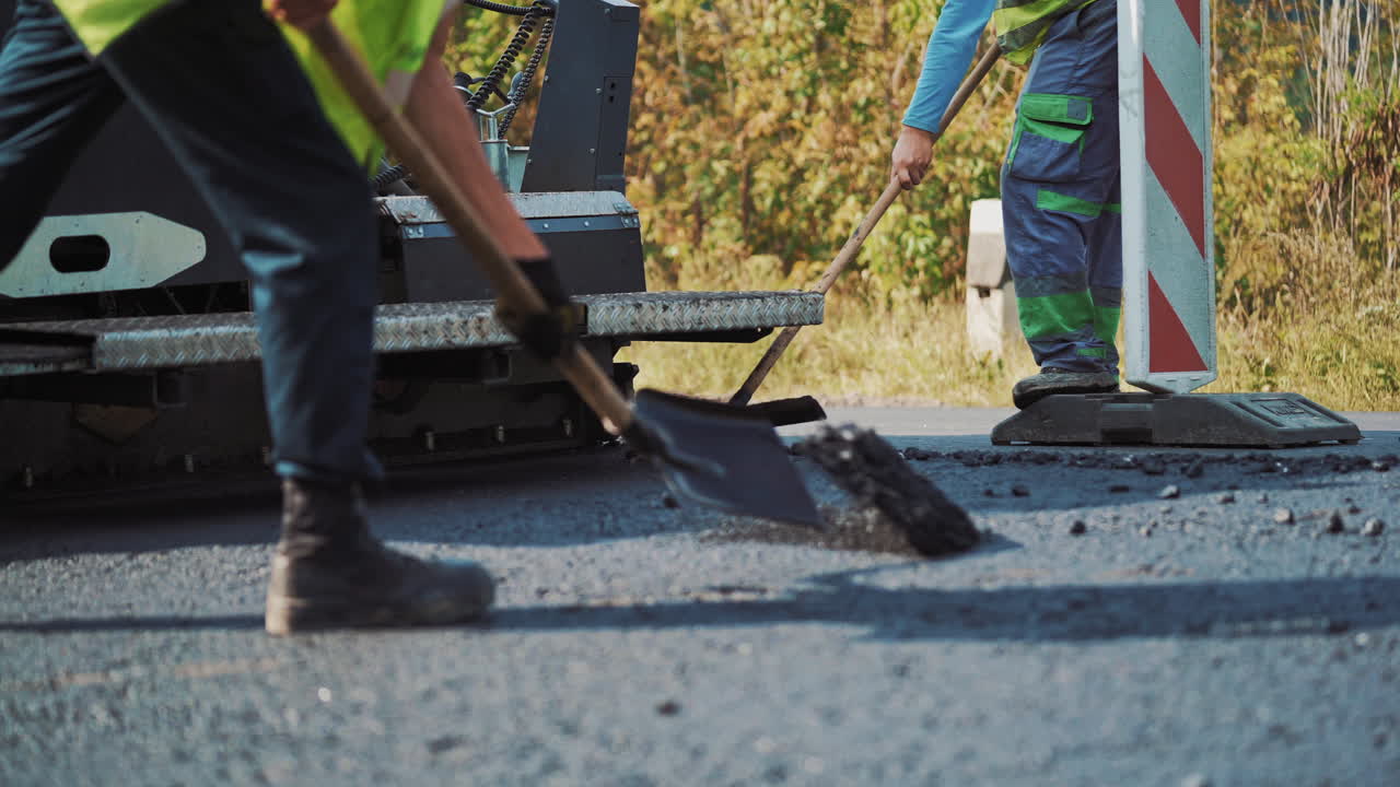 Teamwork at asphalt construction. Workers making asphalt with shovels at road construction