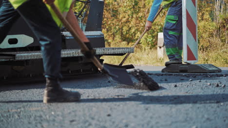 teamwork at asphalt construction. workers making asphalt with shovels at road construction