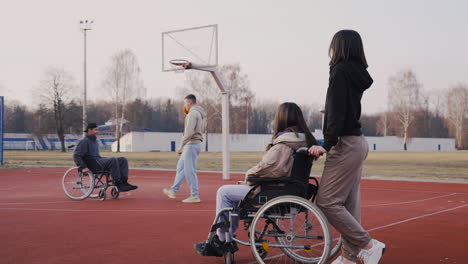 Behinderte-Frau-Im-Rollstuhl-Und-Ihre-Freundin-Beobachten-Ihre-Freunde-Beim-Basketballspielen