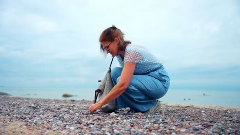 Una-Mujer-Adulta-Recogiendo-Piedras-En-La-Orilla-Del-Mar-De-La-Playa-De-Karkle-En-Lituania