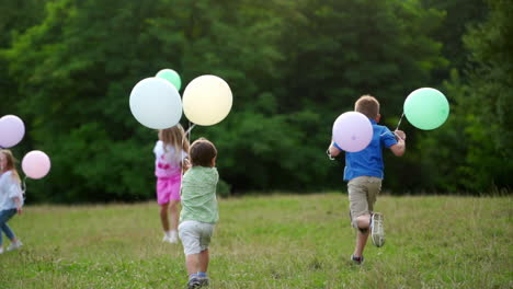 children are running with colorful balloons in the park. boys and girls having fun together outdoor.