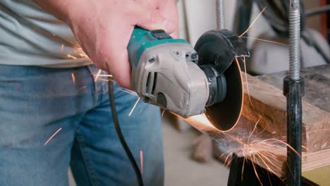 Man-using-an-angle-grinder-to-cut-throug-metal,-with-a-lot-of-sparks