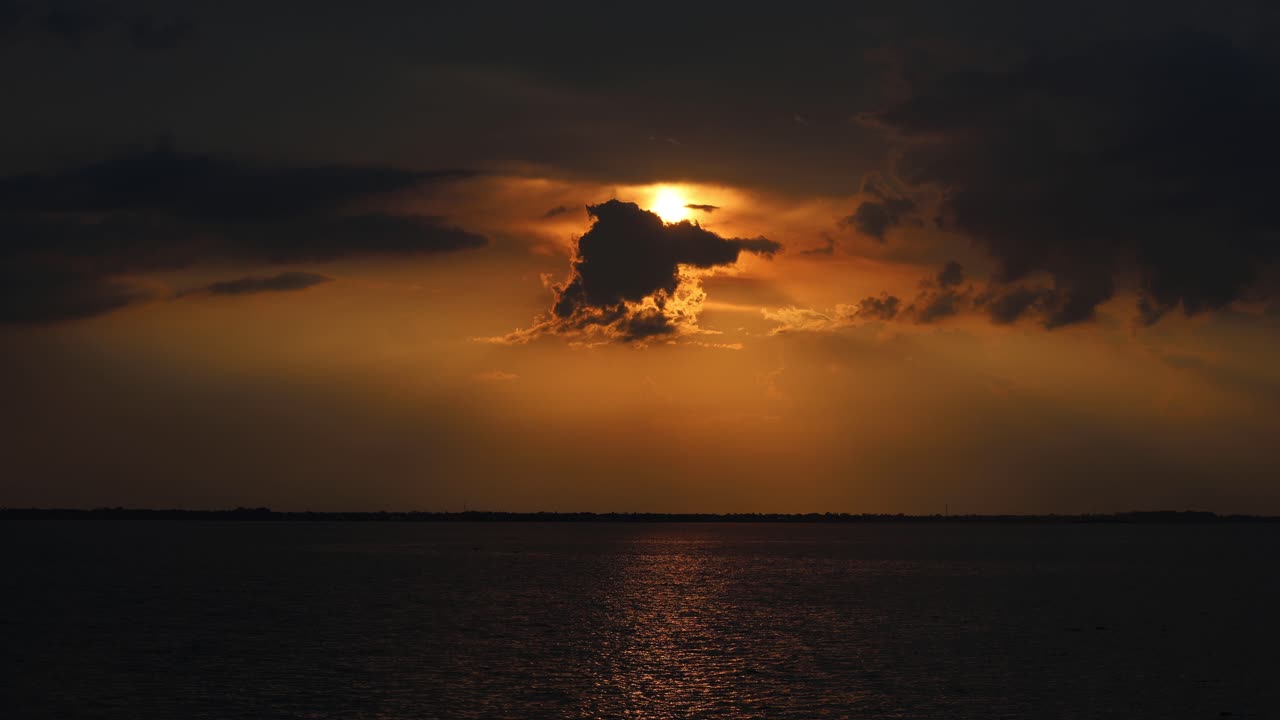 Dunkler, unheilvoller Sonnenuntergang mit bedrohlichen Wolken über einem stimmungsvollen Fluss. Echtzeitaufnahme, die unheimliche Schönheit und Spannung einfängt. Ideal für Themen wie Geheimnis, Drama oder Spannung