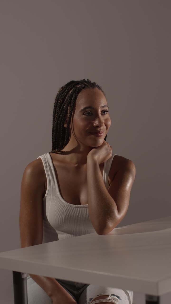 fotografía de belleza en el estudio de una mujer joven con el cabello trenzado largo sentada en la mesa