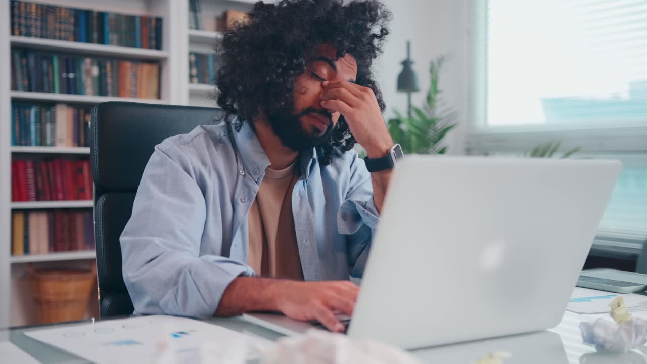 Worried young arabian man businessman upset grabs face looking at laptop screen