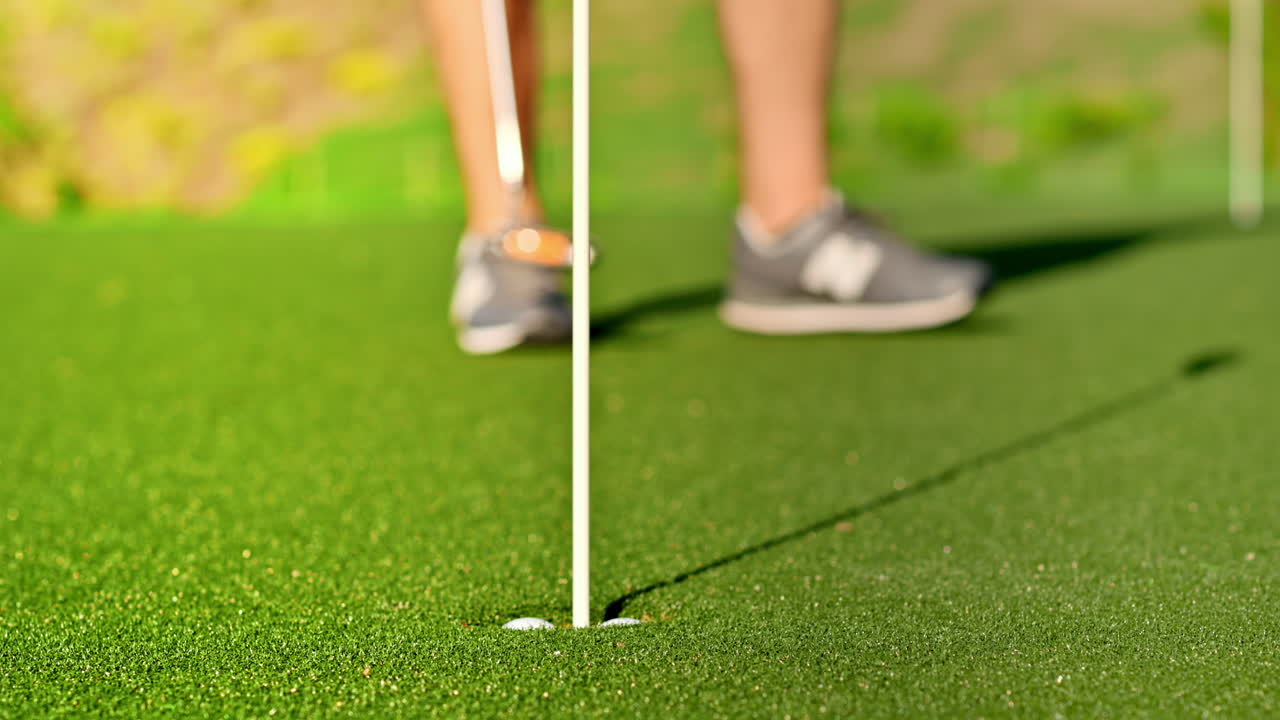 Close up of a man getting a golf ball into the hole